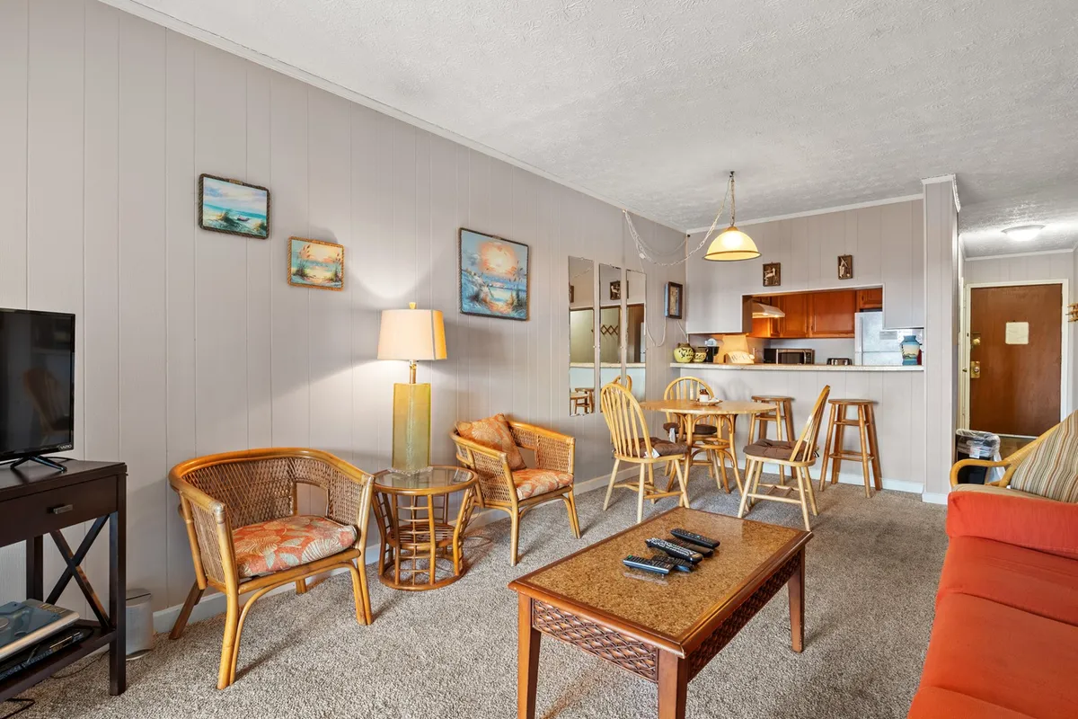 A welcoming dining/living area with a comfortable sofa, coffee table, and a brightly lit, inviting atmosphere. Artwork and lighting fixtures contribute to a social ambiance, suggesting a space where families gather to dine, socialize, and share stories.