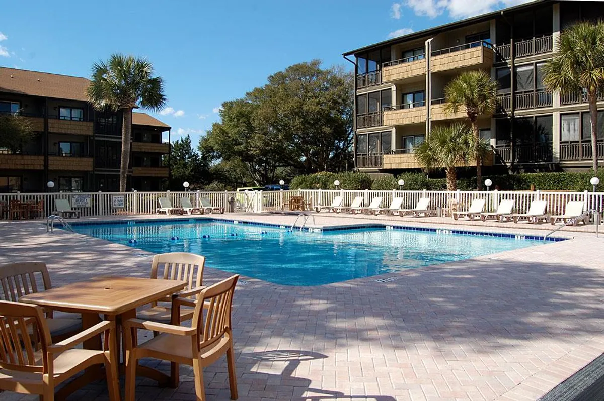 The hero image features a sparkling swimming pool surrounded by inviting lounge chairs and a cozy outdoor dining table, set against the soft glow of a sunset. The scene suggests an atmosphere perfect for swimming, sunbathing, and relaxing with friends or family, with plenty of space for socializing or enjoying a leisurely evening barbecue.