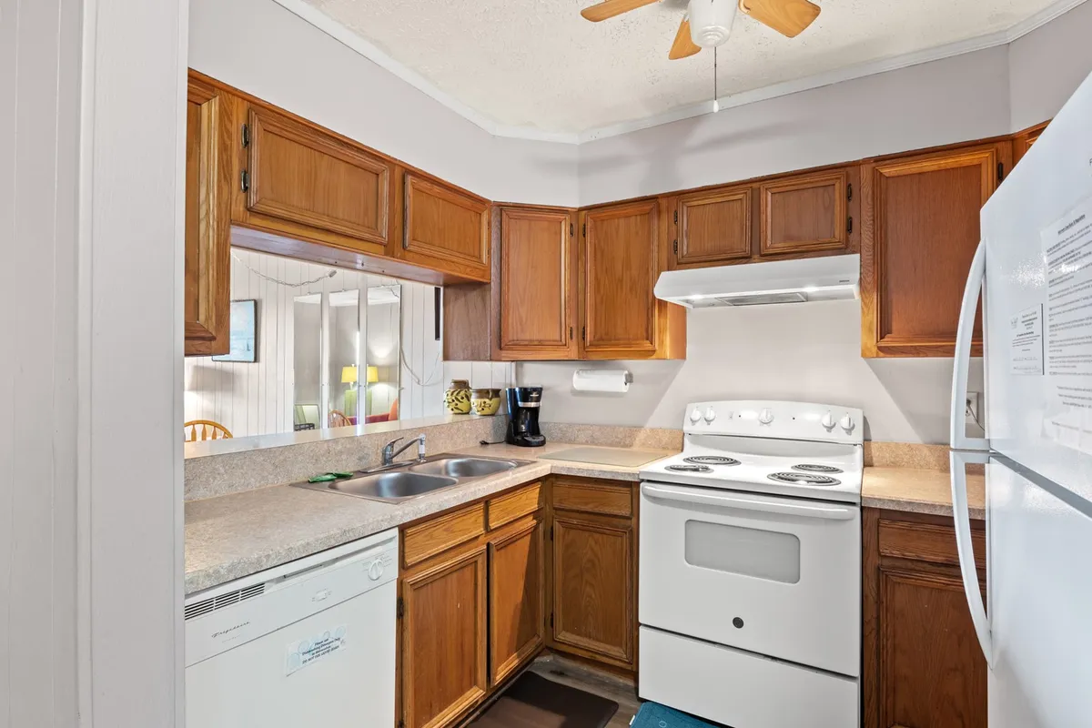 A cozy kitchen scene featuring a spacious countertop, white full-size appliances, and wooden cabinets. The countertop is cleared and ready for meal prep, while kitchen essentials are visible. The warm lighting highlights the inviting and functional nature of the space.