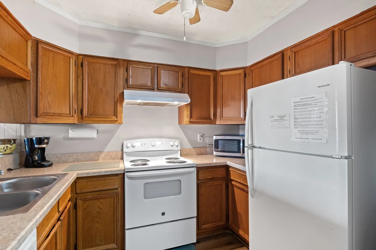 A homey kitchen setup with visible kitchen cabinets, a large stove, full-size refrigerator, and a clean sink area. The space looks ready for preparing family meals and hosting gatherings, emphasizing functionality and warmth.